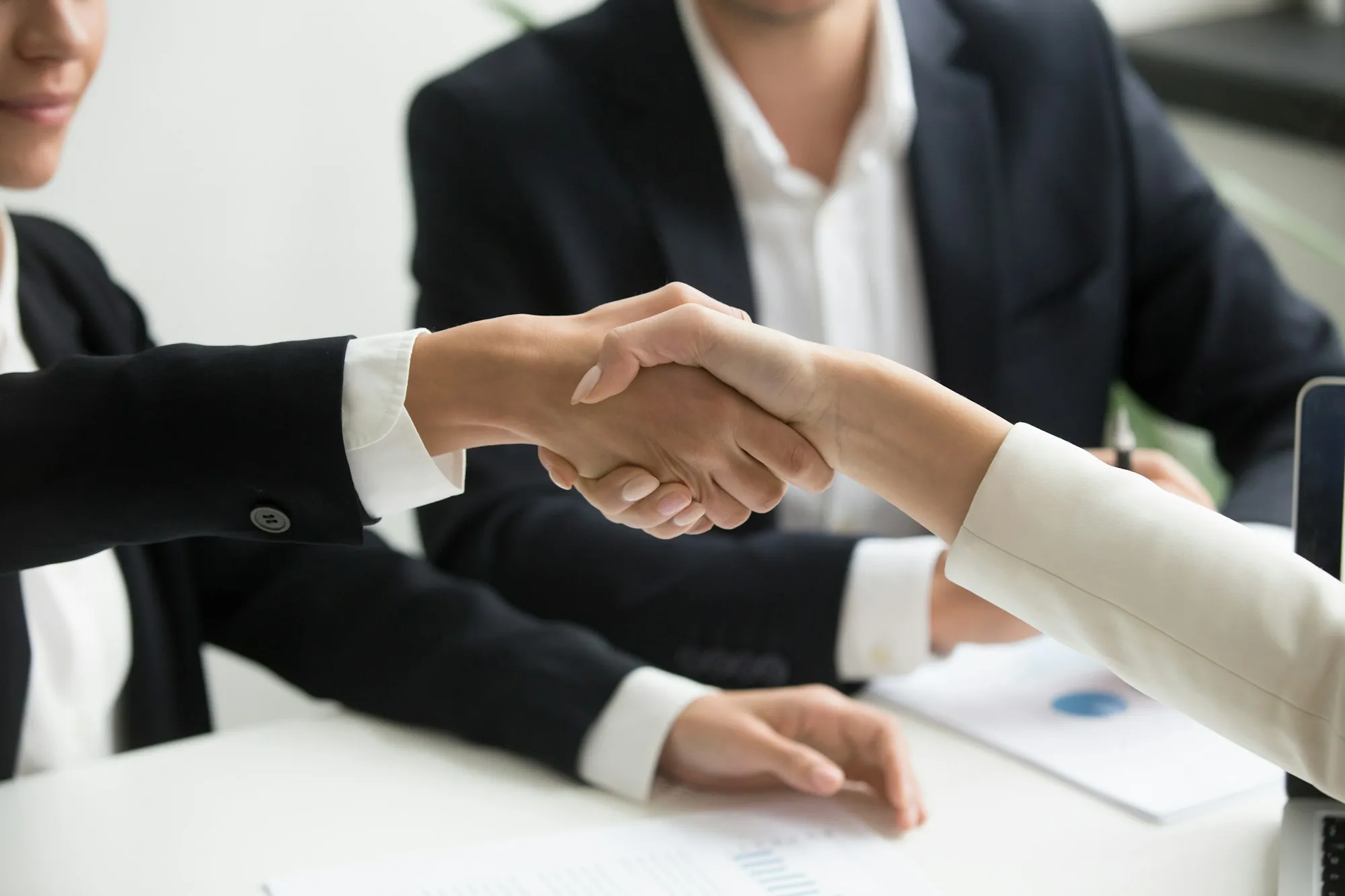 Handshake over a desk with papers as a buyer agrees to an earnest money deposit on a home in Shafter, California