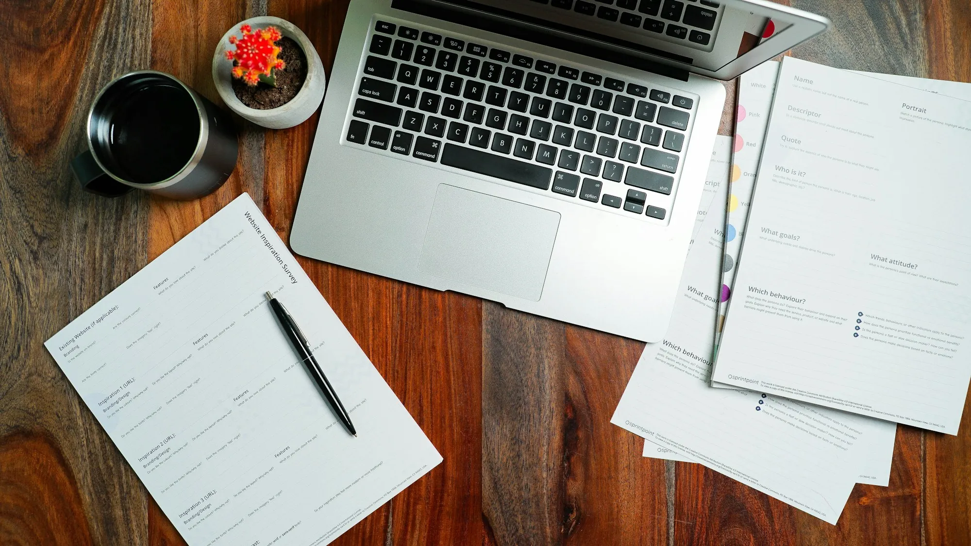 Laptop, papers and a pen on a wooden desk