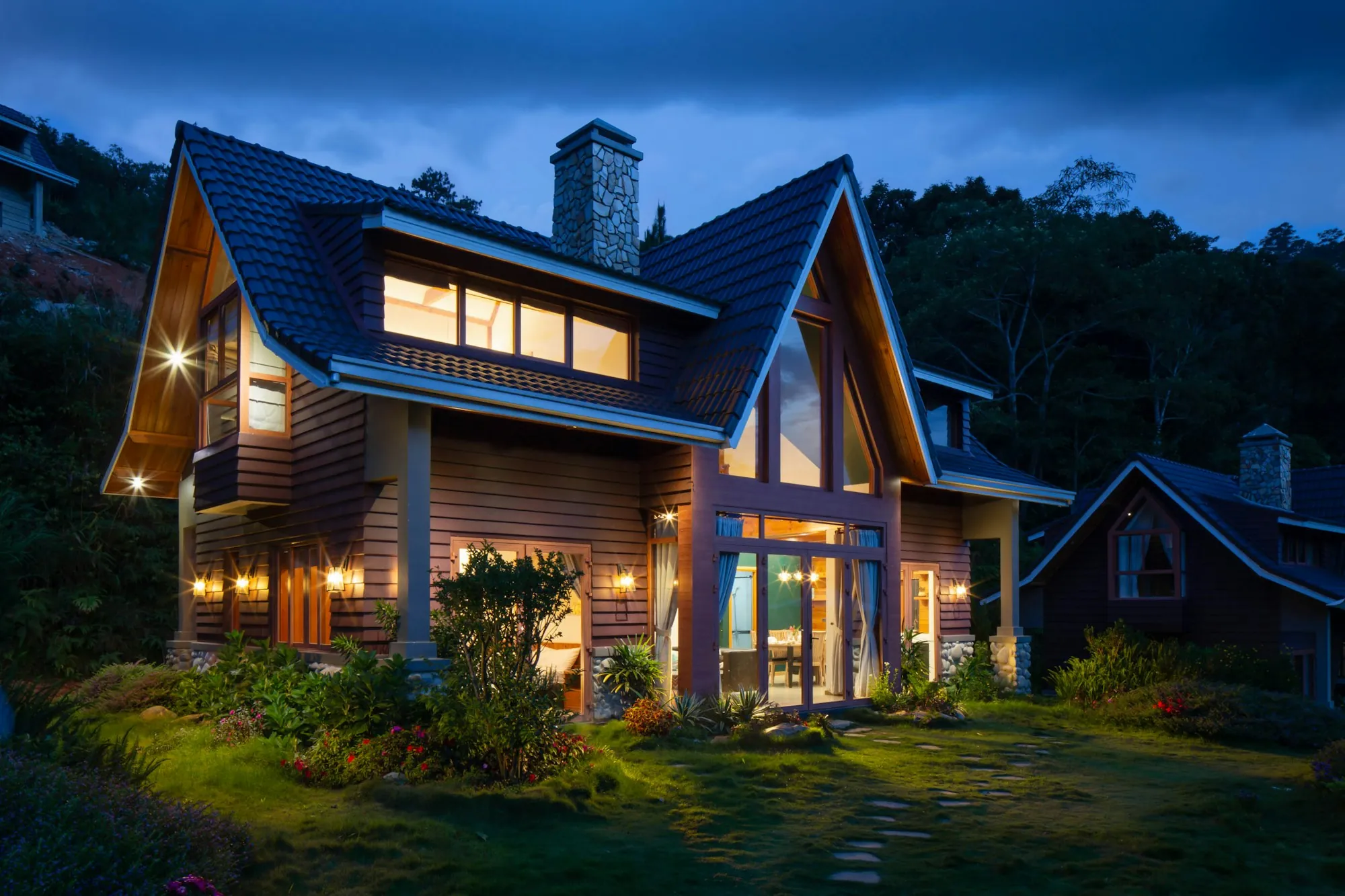 Two-story wood-sided house with glowing windows at dusk
